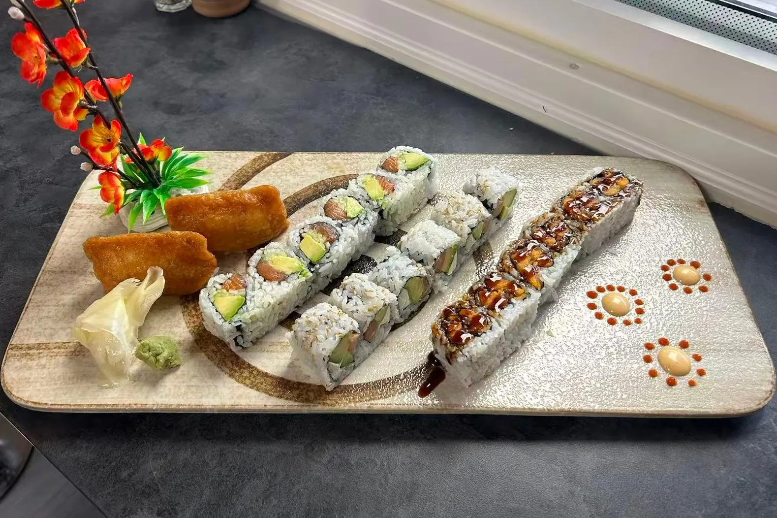 Platter with a variety of sushi rolls, garnished with flowers at Dharma Sushi & Grill, a Japanese Restaurant in Schenectady