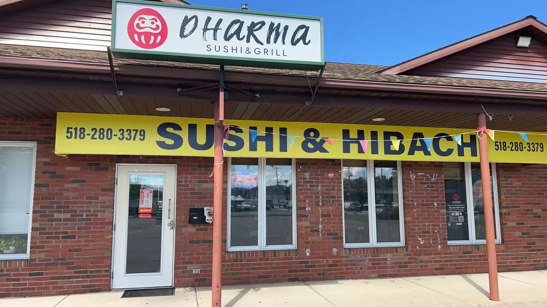 The exterior storefront of Dharma Sushi & Grill with contact number display at Dharma Sushi & Grill, a Japanese Restaurant in Schenectady