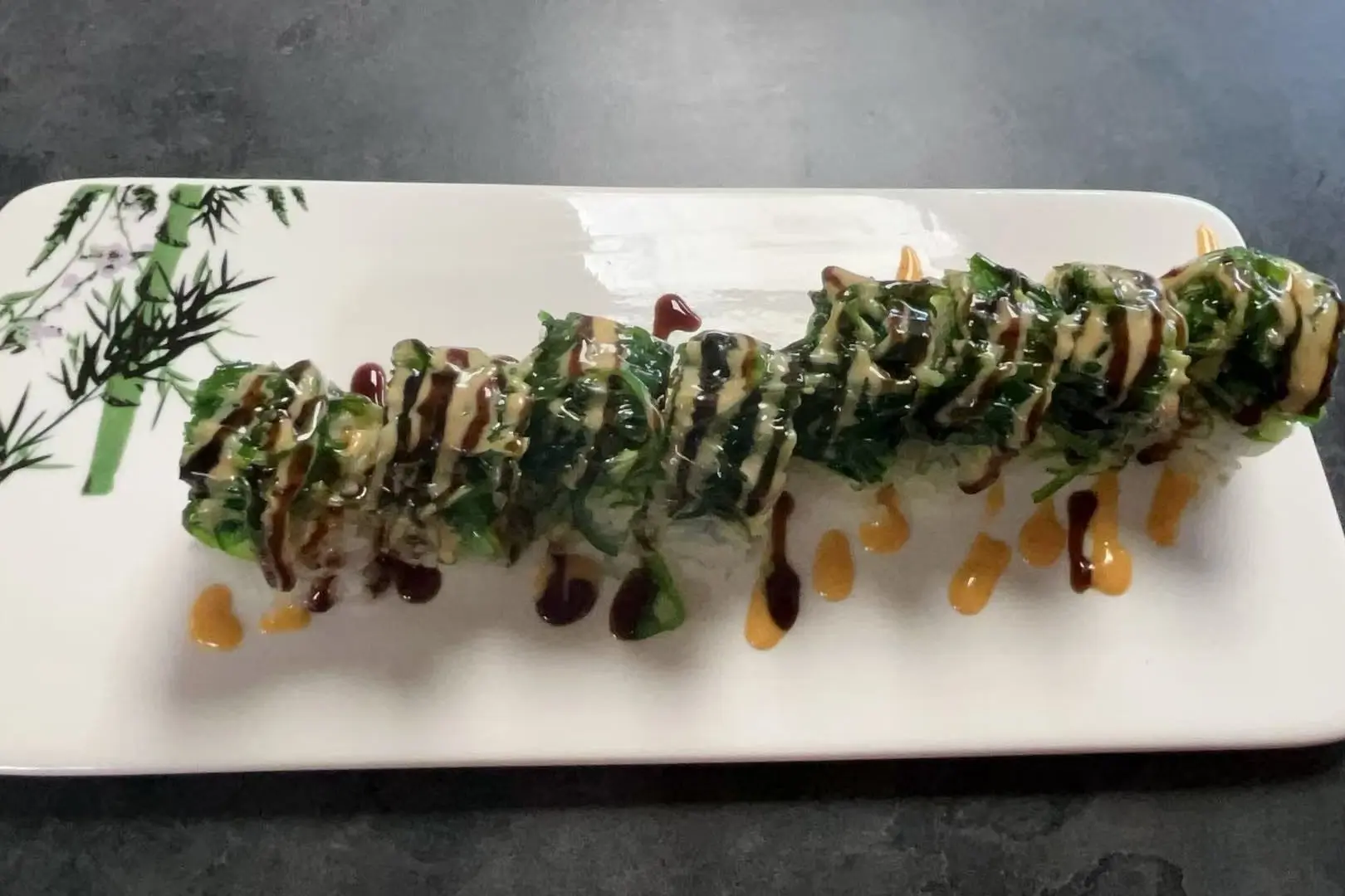 Sushi roll topped with seaweed and drizzled with sauces at Dharma Sushi & Grill, a Japanese Restaurant in Schenectady
